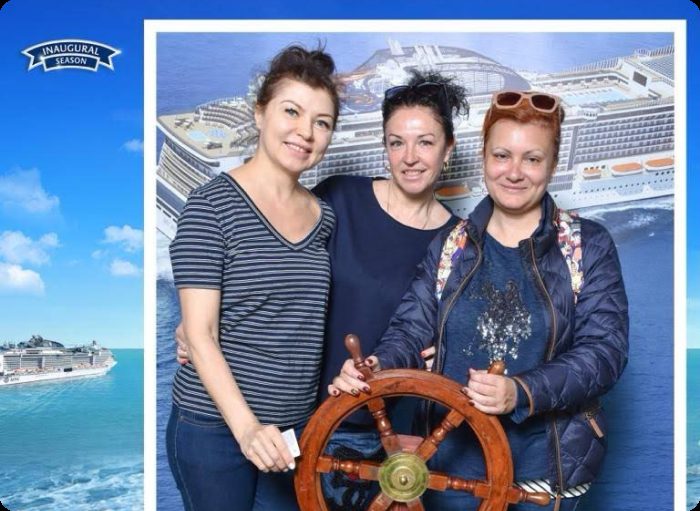 Группа туристов фотографируется у штурвала на фотозоне круизного лайнера